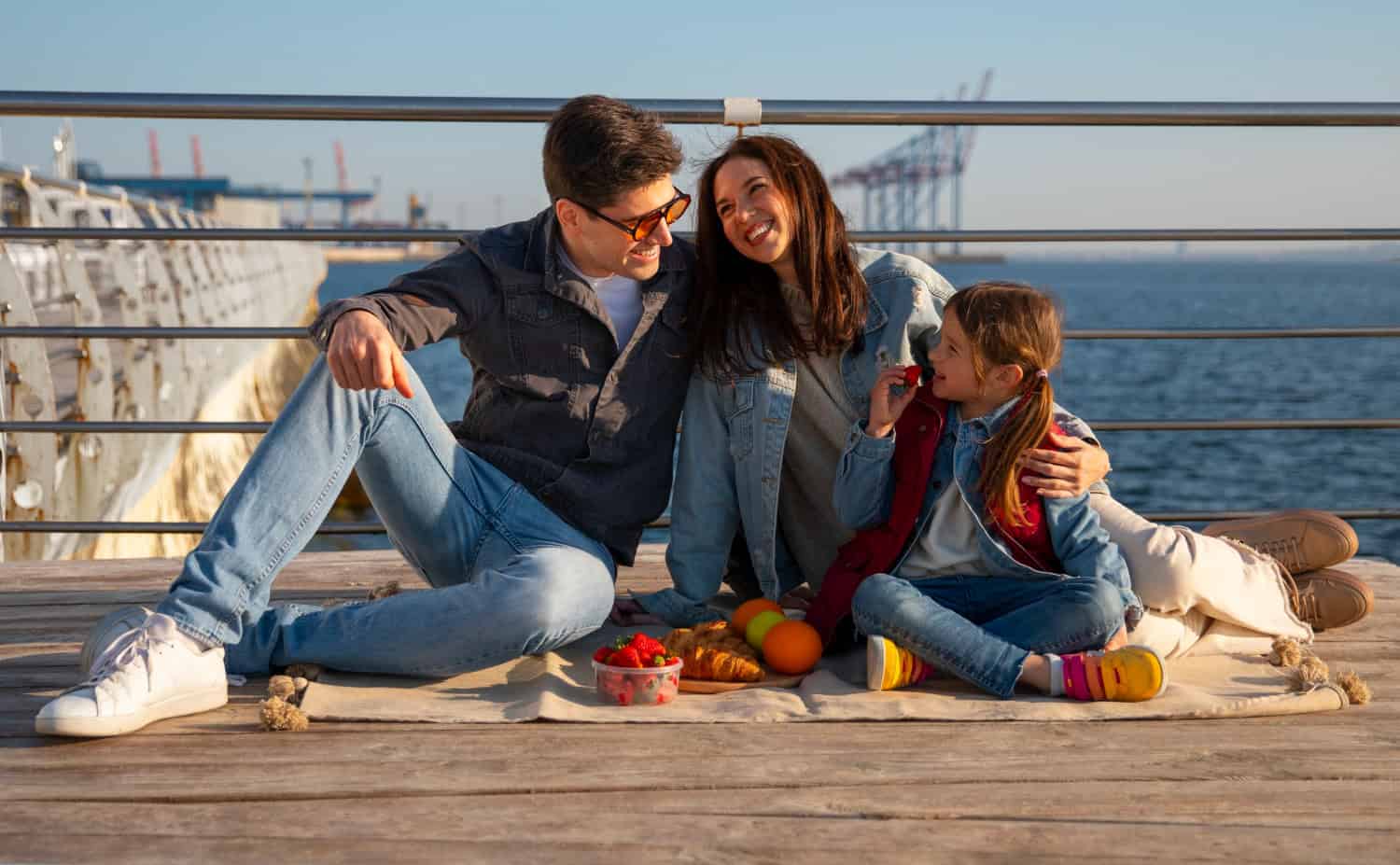 Family enjoying a picnic on a pier with a harbor background, showcasing community and outdoor leisure in Victoria.